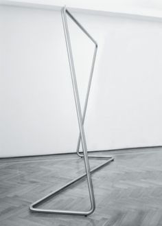 a metal object sitting on top of a wooden floor next to a white wall in an empty room