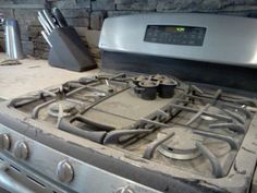 a stove top oven sitting in front of a stone wall next to a knife holder