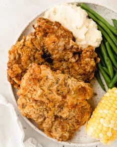 fried chicken, mashed potatoes and green beans on a white plate with corn on the cob