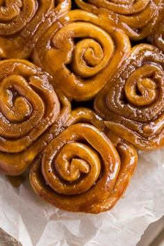 some cinnamon rolls are sitting on wax paper