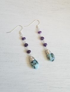 Make a unique statement in these gorgeous natural gemstone earrings. These earrings feature natural purple Amethyst stones each hand wire wrapped together and accented with a one of a kind Larimar teardrop stone that is also hand wire wrapped with Sterling Silver wire. Genuine Sterling Silver ear wires that are safe for all wearers. Earrings hang approximately 2 3/4 inches. The stunning colors of these two energy filled stones make a great pair and add a festive boho vibe to any outfit. **Please Bohemian Gemstone Teardrop Earrings, Amethyst Gemstone Teardrop Dangle Earrings, Bohemian Drop Gemstone Earrings, Teardrop Natural Stone Earrings For Healing, Dangle Earrings Boho, Amethyst Stones, Earrings Statement, Earrings Boho, Boho Vibe