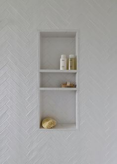 a white shelf with some items on it in a room that is decorated with herringbone tiles