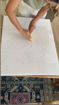 a woman is using a sponge to clean the surface of a piece of art work