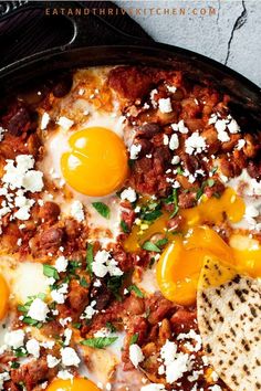 a skillet filled with eggs, meat and cheese on top of tortilla chips