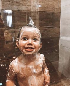 a little boy that is sitting in the bathtub with soap on his face and body