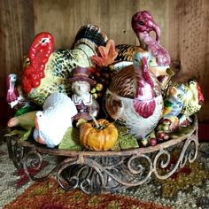 a bowl filled with figurines sitting on top of a metal stand next to a rug