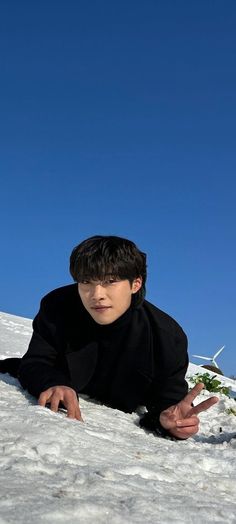 a man laying in the snow wearing a black suit