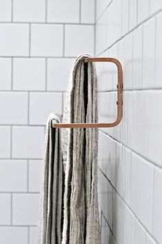 a towel rack in the corner of a bathroom with white tile walls and flooring