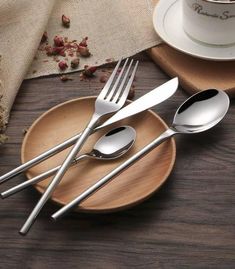 three forks and two spoons on a plate with a cup of coffee in the background