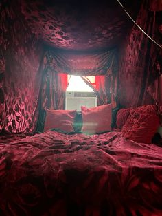 a bed with red sheets and pillows in a room that looks like it has been made