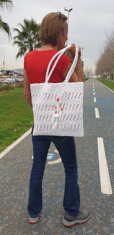 a woman walking down the road carrying a white bag