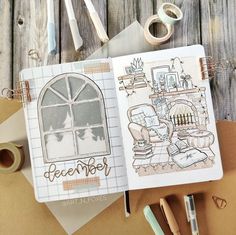 an open notebook with drawings on it next to some crafting supplies and paper tape