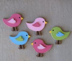 five wooden birds sitting on top of a floor next to each other in different colors