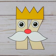 a paper crown with eyes and a nose on top of wood planks, cut out to look like a man's face