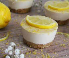 three lemon cheesecakes on a wooden table with flowers and lemon slices around them