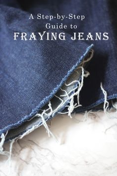 a pair of blue jeans with frayed edges on a white marble surface, close up