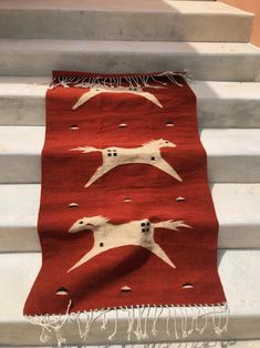 a red rug with white dogs on it sitting on the steps in front of some stairs