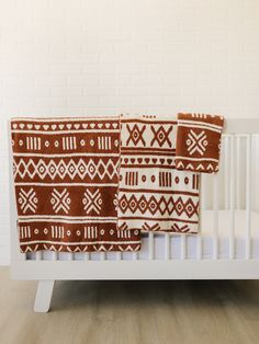 two brown and white blankets sitting on top of a crib next to a brick wall