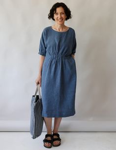 a woman standing in front of a white wall holding an umbrella