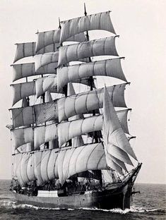 an old photo of a sailboat sailing in the ocean with sails down and no people on board