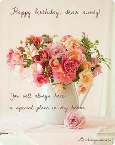 a white vase filled with pink flowers on top of a table