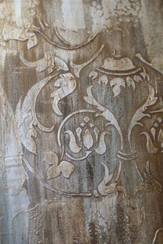 an ornate design on the side of a metal container with peeling paint and rust stains