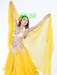 a woman in a yellow belly dance outfit with her arms outstretched and hands behind her head