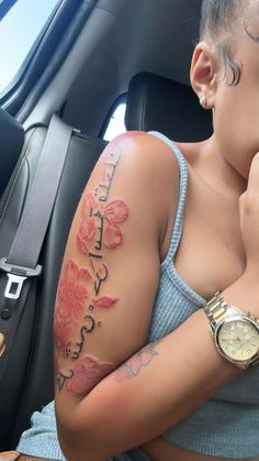 a woman sitting in the back seat of a car with tattoos on her arm and chest