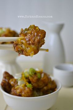 a white bowl filled with food and chopsticks sticking out of the meatballs