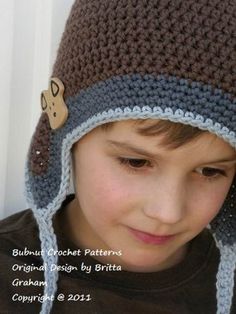 a young boy wearing a crocheted hat with a button on the front and side