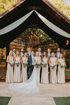 a bride and groom with their bridal party in front of a gazebo at an outdoor wedding