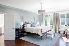 a bedroom with hardwood floors and blue walls, white bedding, chandelier