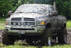 the truck is driving through mud in the woods