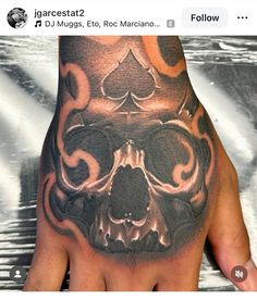 a man's hand with a skull and playing cards tattoo on the middle of it