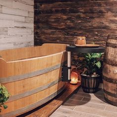 a wooden tub sitting on top of a tiled floor next to two large wooden barrels