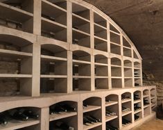 a wine cellar filled with lots of bottles next to a wall covered in cement shelves