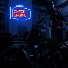 a man standing next to a motorcycle in a room with neon signs on the wall