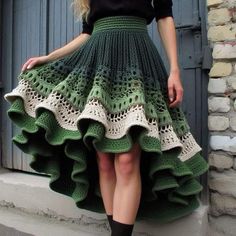 a woman wearing a green and white crocheted skirt with ruffles on the bottom