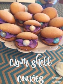 some cookies are sitting on a plate with purple icing and blue pearls around them