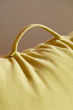 a close up view of a yellow pillow with a knot on the back of it