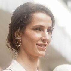 a close up of a person wearing earrings and a white shirt with an earring