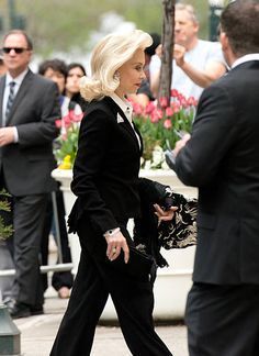 a woman in black suit walking down the street