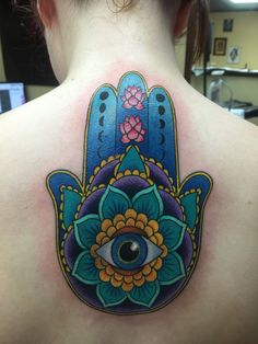 a woman's back with a hamsa tattoo on her shoulder and an eye in the center