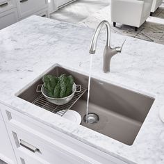 a kitchen sink with a metal strainer next to it on a marble counter top