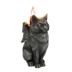 a black cat statue sitting on top of a white table next to a lit candle