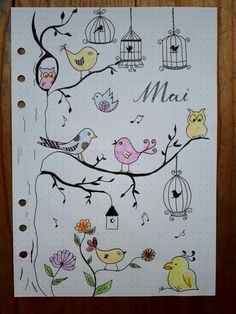 a notepad with birds and birdcages on it, next to a pen