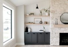 a living room filled with furniture and a fire place next to a brick wall covered in shelves