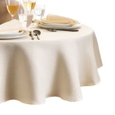 the table is set with wine glasses, plates and utensils for two people