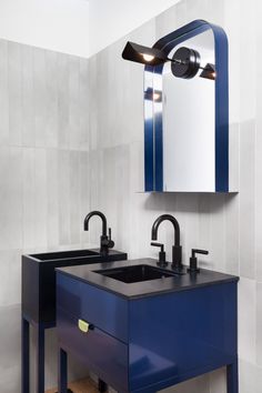 a bathroom with two sinks and a mirror on the wall next to it is blue