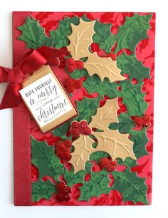 a christmas card with holly and mistlet leaves on it, tied with a red ribbon